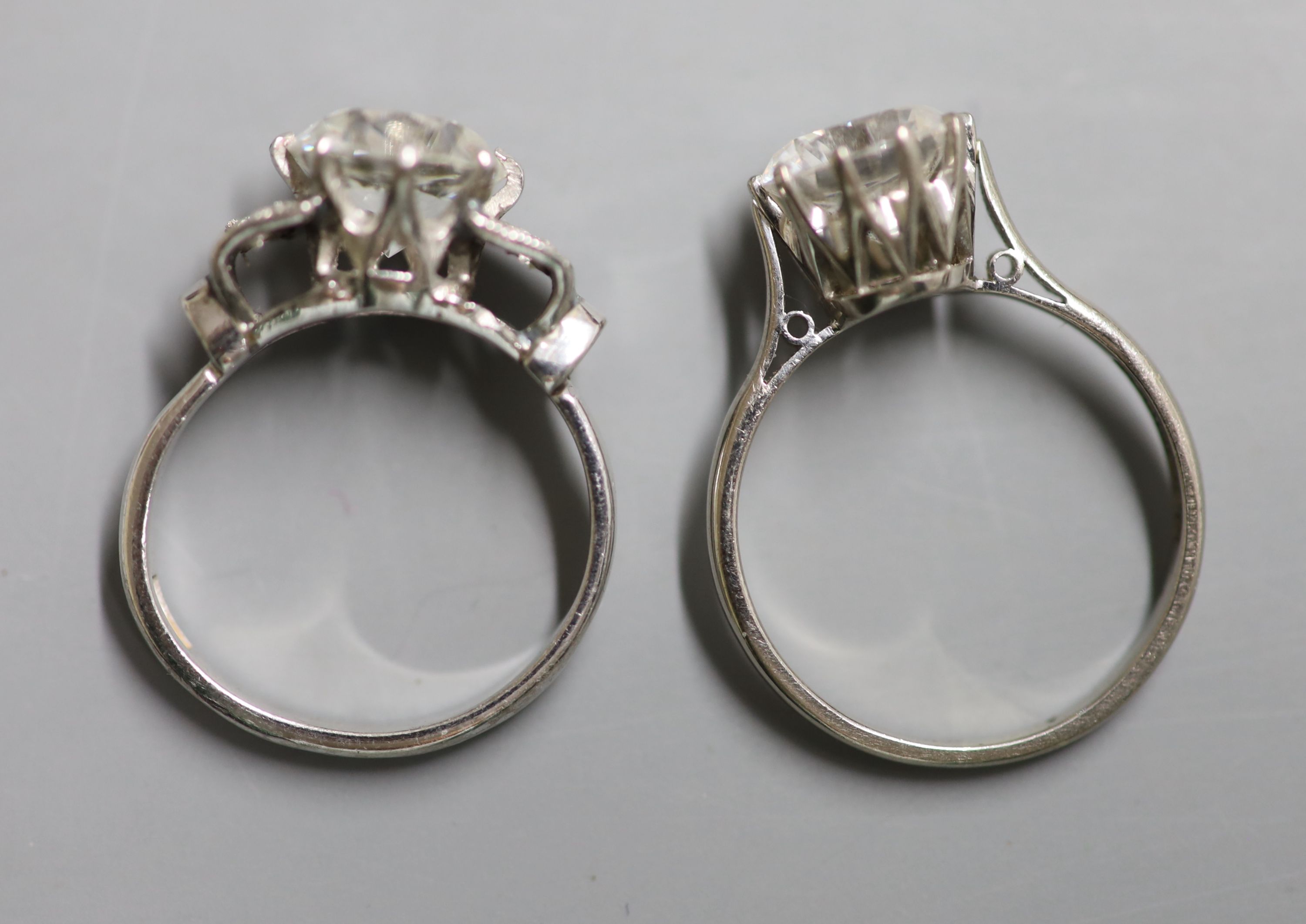 A white metal (stamped plat) single stone moissanite? and four stone diamond set dress ring and an 18ct gold